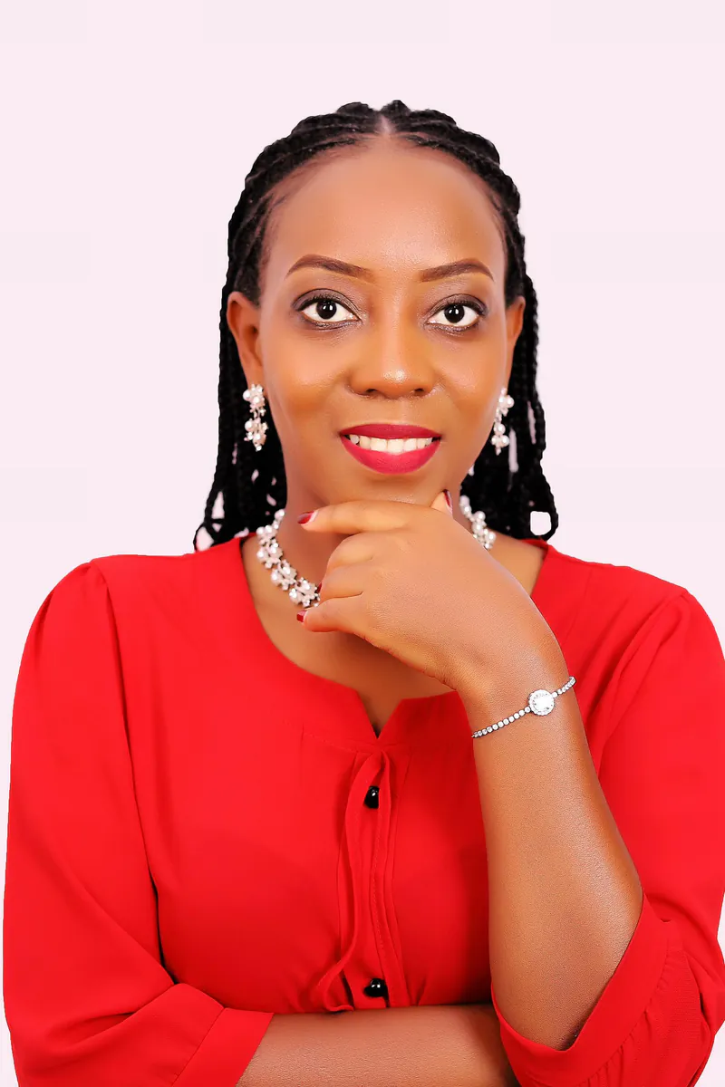 Peninah Joy Kansiime, founder of Emet Coaching & Consultancy, smiling in a red blouse